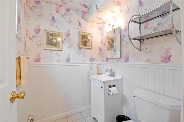 half bath featuring wainscoting, toilet, tile patterned flooring, and vanity
