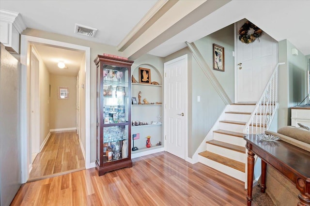 corridor featuring light wood-type flooring, stairs, and baseboards
