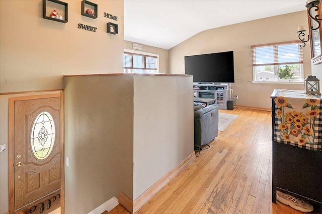 foyer entrance featuring light wood finished floors, lofted ceiling, healthy amount of natural light, and baseboards