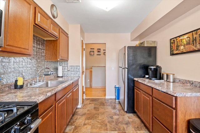 kitchen with a sink, decorative backsplash, light countertops, brown cabinets, and stone finish flooring
