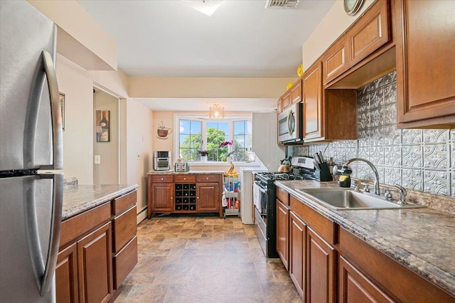 kitchen with stainless steel appliances, a sink, brown cabinetry, stone finish floors, and decorative backsplash