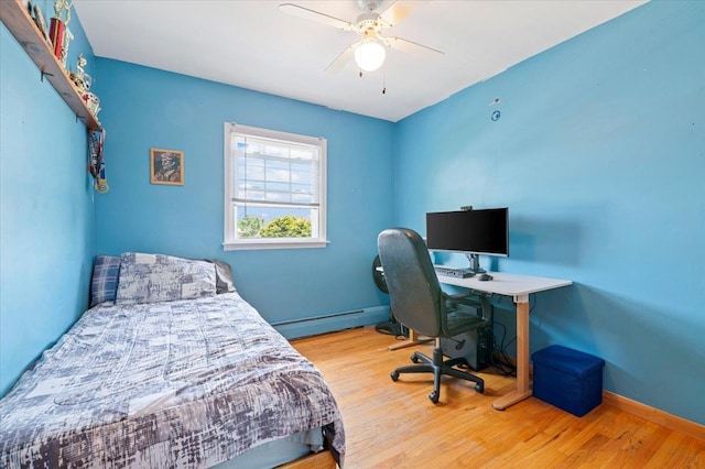 bedroom with a baseboard radiator, wood finished floors, a ceiling fan, baseboards, and an office area