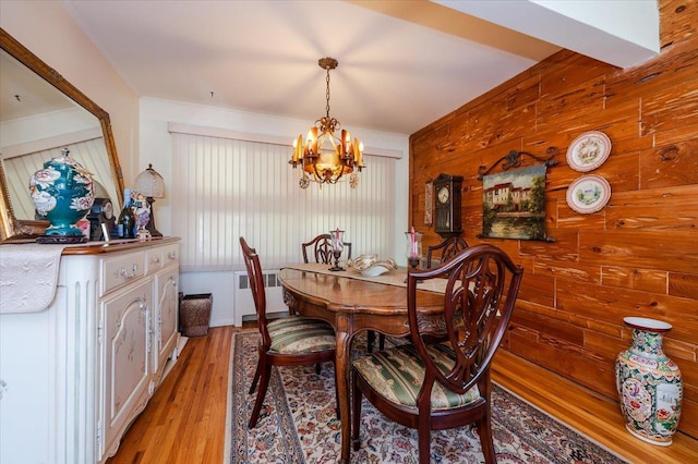 3176 Benjamin Rd, Oceanside, NY 11572 - dining space featuring radiator heating unit, a chandelier, wooden walls, and light wood-type flooring