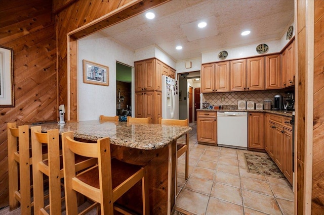 3176 Benjamin Rd, Oceanside, NY 11572 - kitchen featuring white appliances, a breakfast bar area, decorative backsplash, light stone countertops, and a peninsula
