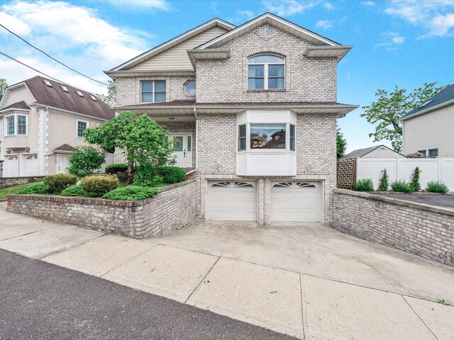 12 Pleasant Ave, Port Washington, NY 11050 - view of front of house featuring brick siding, a garage, driveway, and fence