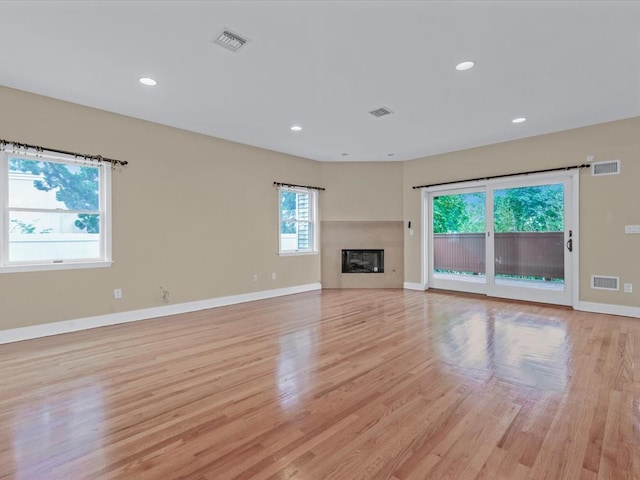 12 Pleasant Ave, Port Washington, NY 11050 - unfurnished living room featuring light wood-type flooring, baseboards, recessed lighting, and a glass covered fireplace
