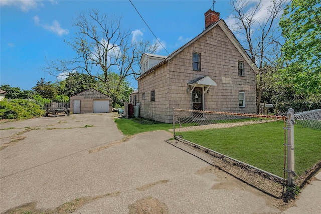 view of front of home featuring a detached garage, a chimney, and an outbuilding
