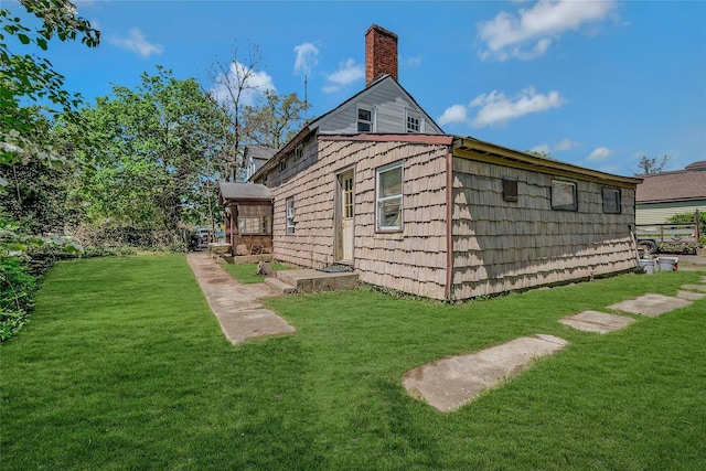 back of house featuring a yard and a chimney