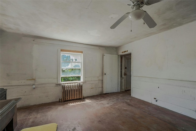 spare room with radiator heating unit, ceiling fan, and concrete flooring