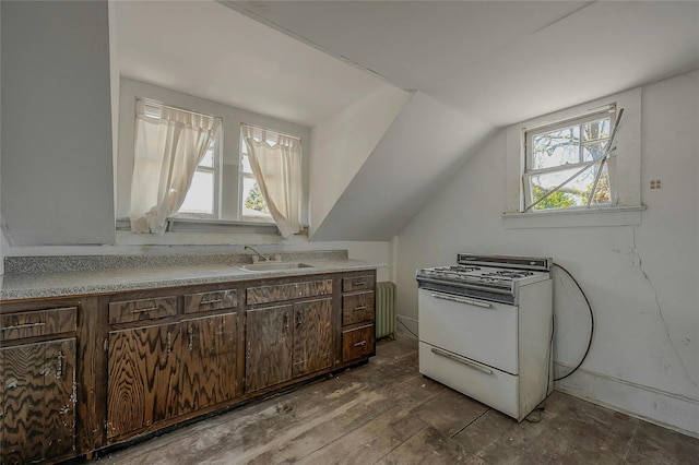 kitchen with gas range gas stove, a sink, dark brown cabinets, dark wood finished floors, and light countertops