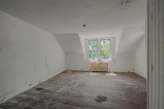 additional living space featuring radiator, lofted ceiling, wood-type flooring, and baseboards