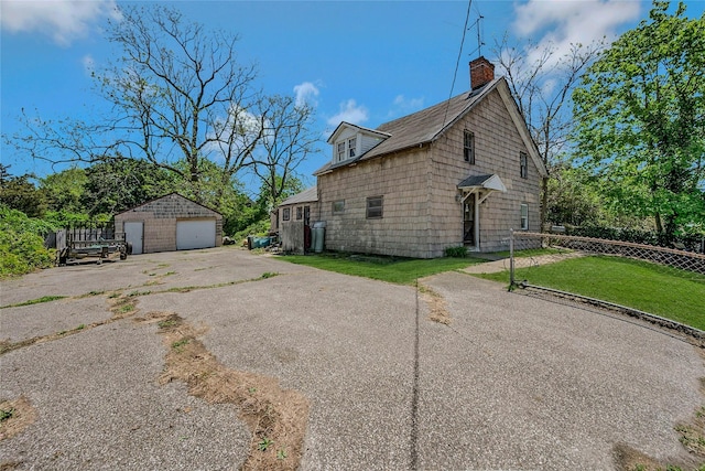 view of side of home featuring a garage, an outbuilding, a chimney, and asphalt driveway