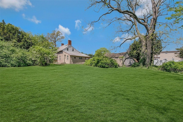 view of green lawn with an outbuilding and a storage shed