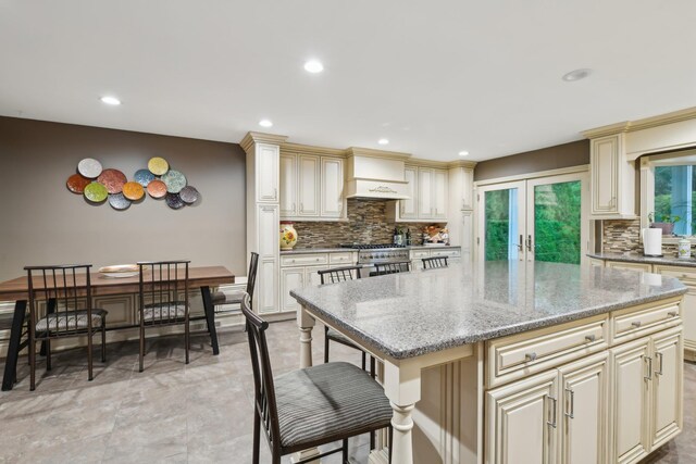 98 Beach Rd, Westhampton Beach, NY 11978 - kitchen with cream cabinetry, premium range hood, tasteful backsplash, light stone counters, and recessed lighting