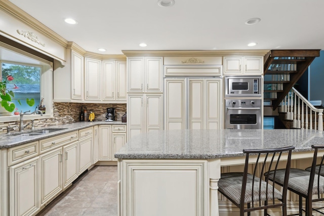 98 Beach Rd, Westhampton Beach, NY 11978 - kitchen with built in appliances, cream cabinetry, a sink, a kitchen breakfast bar, and decorative backsplash