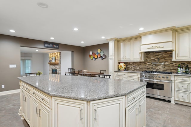 98 Beach Rd, Westhampton Beach, NY 11978 - kitchen featuring high end stove, cream cabinetry, custom exhaust hood, a center island, and tasteful backsplash