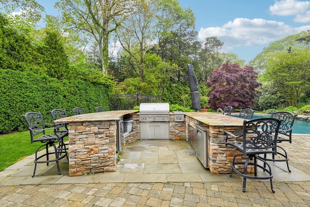 98 Beach Rd, Westhampton Beach, NY 11978 - view of patio featuring an outdoor kitchen, area for grilling, fence, and view of wooded area