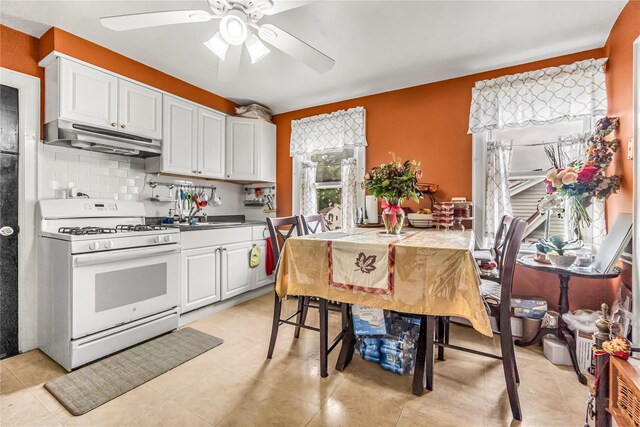 16 Rollhaus Pl, Port Chester, NY 10573 - kitchen with white gas range oven, under cabinet range hood, ceiling fan, decorative backsplash, and white cabinets