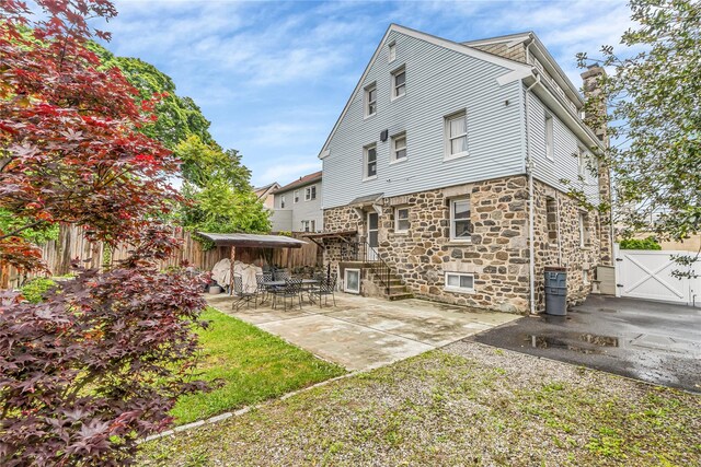 16 Rollhaus Pl, Port Chester, NY 10573 - rear view of house featuring stone siding, a chimney, a gate, and a patio area