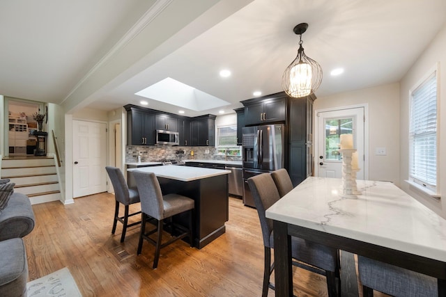 22 Willow Pl, Middletown, NY 10940 - kitchen featuring appliances with stainless steel finishes, light countertops, a kitchen breakfast bar, backsplash, and a center island