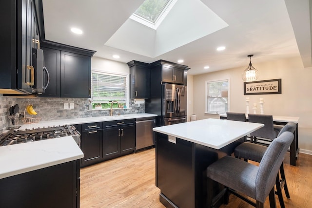 22 Willow Pl, Middletown, NY 10940 - kitchen featuring appliances with stainless steel finishes, backsplash, dark cabinetry, a skylight, and light wood-style flooring
