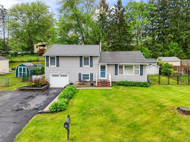 22 Willow Pl, Middletown, NY 10940 - split level home with a storage shed, asphalt driveway, an attached garage, a shingled roof, and an outdoor structure