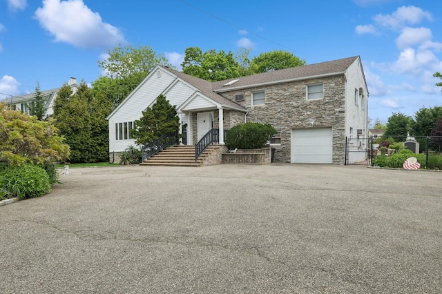 2525 Beverly Rd, Merrick, NY 11566 - view of front of home featuring stone siding, a gate, asphalt driveway, a garage, and fence