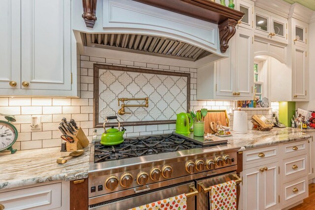 110 Red Spring Ln, Glen Cove, NY 11542 - kitchen featuring high end stove, premium range hood, decorative backsplash, glass insert cabinets, and white cabinets