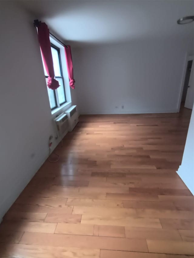 spare room with light wood-style flooring and a wall unit AC