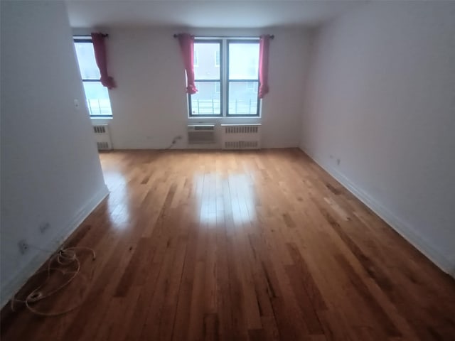 spare room with radiator heating unit, light wood-style flooring, and baseboards