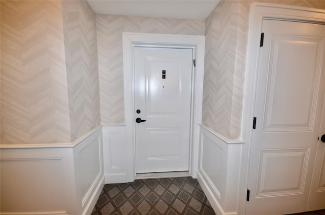 doorway with wallpapered walls, a decorative wall, and wainscoting