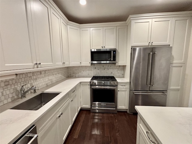 kitchen with stainless steel appliances, a sink, white cabinets, and tasteful backsplash