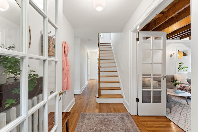 stairway with french doors, wood finished floors, and baseboards