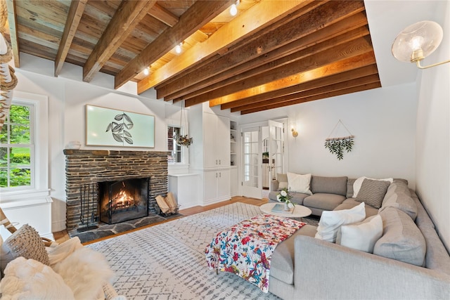 living room with beam ceiling, wooden ceiling, and a lit fireplace