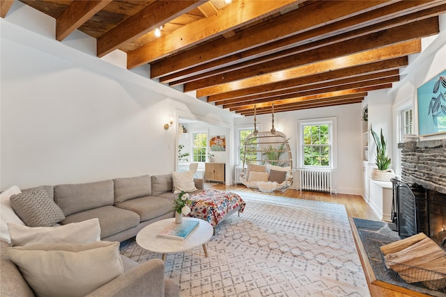 living area with radiator heating unit, beamed ceiling, wood finished floors, a fireplace, and baseboards