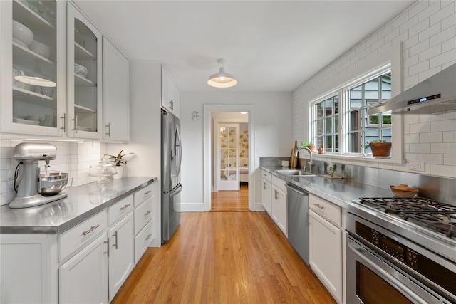 kitchen featuring stainless steel counters, stainless steel appliances, a sink, backsplash, and white cabinets