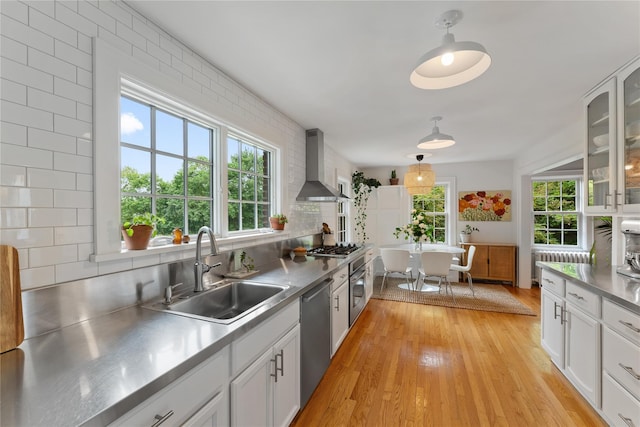 kitchen featuring stainless steel countertops, wall chimney exhaust hood, a sink, and appliances with stainless steel finishes