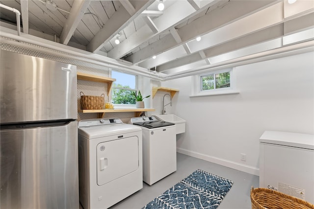 clothes washing area featuring baseboards, healthy amount of natural light, and washing machine and clothes dryer