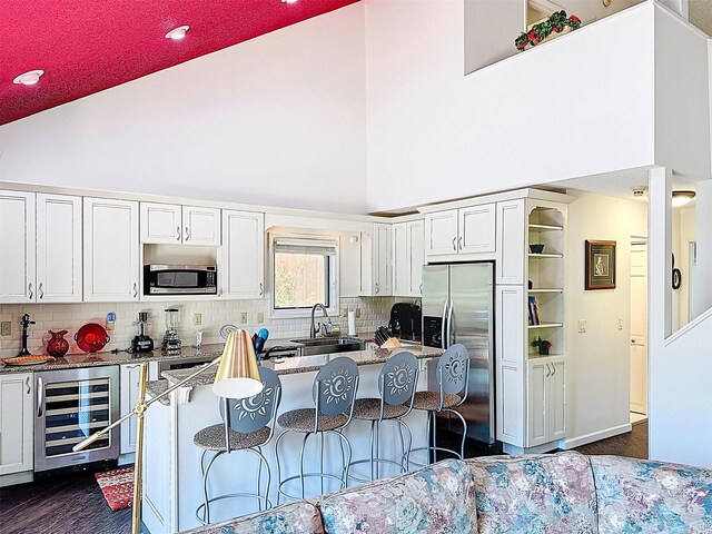 5 Water Lilly Ln, Monticello, NY 12701 - kitchen featuring stainless steel appliances, wine cooler, high vaulted ceiling, white cabinets, and dark wood-type flooring