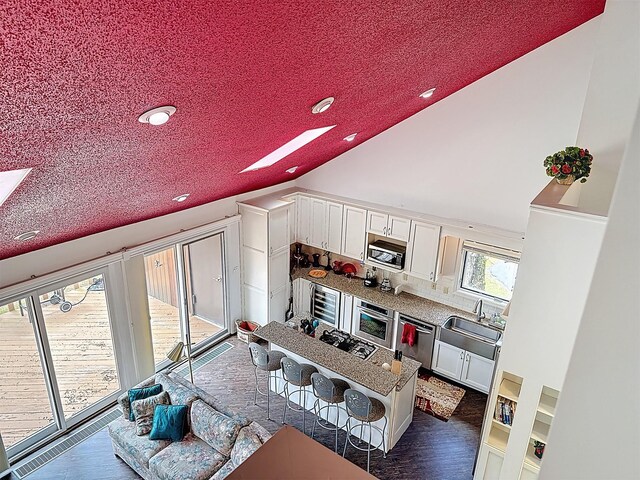 5 Water Lilly Ln, Monticello, NY 12701 - kitchen with stainless steel appliances, white cabinetry, lofted ceiling, a sink, and dark wood-style floors