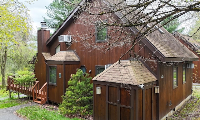 5 Water Lilly Ln, Monticello, NY 12701 - view of home's exterior with a shingled roof, an outbuilding, a deck, and an AC wall unit