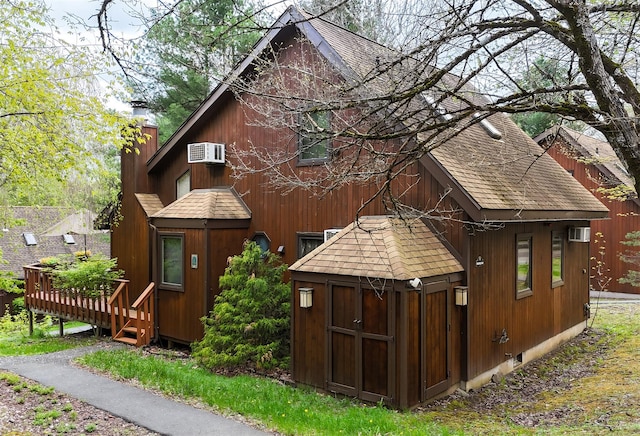 5 Water Lilly Ln, Monticello, NY 12701 - view of property exterior featuring roof with shingles, a chimney, an outdoor structure, and a wall unit AC