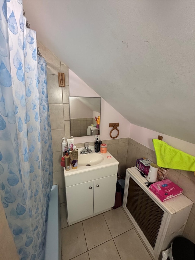 702 Tower Ct, Uniondale, NY 11553 - bathroom with tile walls, lofted ceiling, tile patterned flooring, vanity, and shower / bath combo