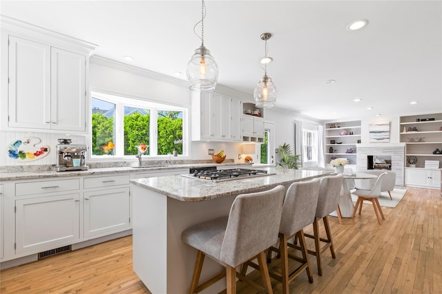 2 Robert Crisfield Pl, Rye, NY 10580 - kitchen with stainless steel gas stovetop, crown molding, healthy amount of natural light, white cabinets, and a center island