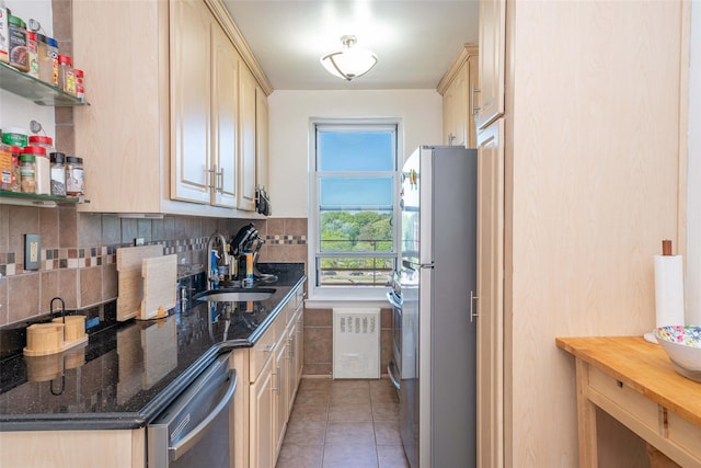 kitchen with appliances with stainless steel finishes, a sink, light brown cabinetry, tasteful backsplash, and light tile patterned flooring