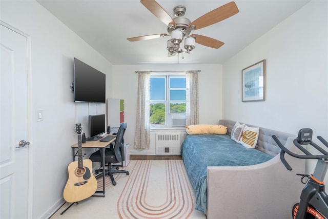 bedroom featuring radiator, an office area, baseboards, and a ceiling fan