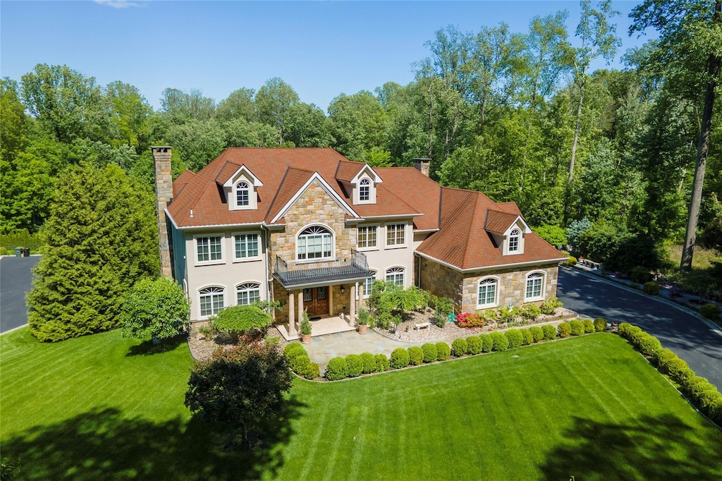 42 Young Rd, Katonah, NY 10536 - view of front of home with stone siding, a chimney, a front lawn, and stucco siding