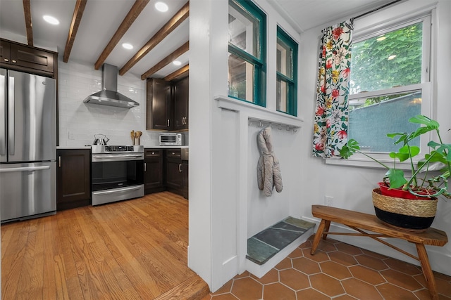 1219 Maple Ave, Peekskill, NY 10566 - kitchen with appliances with stainless steel finishes, wall chimney exhaust hood, backsplash, light countertops, and dark brown cabinets