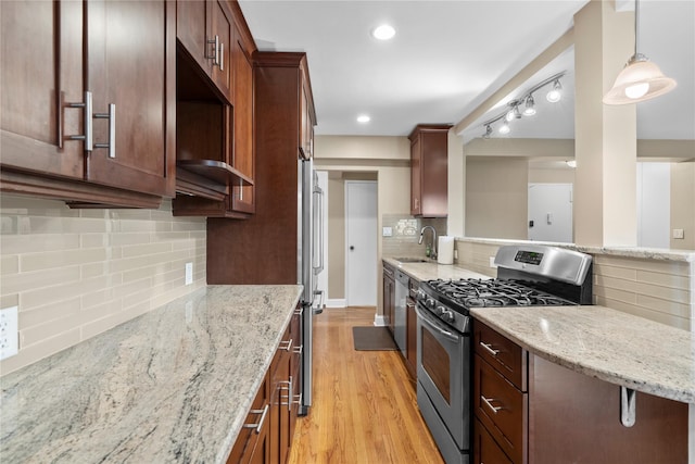 80 E Hartsdale Ave Unit 520, Hartsdale, NY 10530 - kitchen with stainless steel gas range oven, backsplash, light wood-style flooring, a sink, and light stone counters