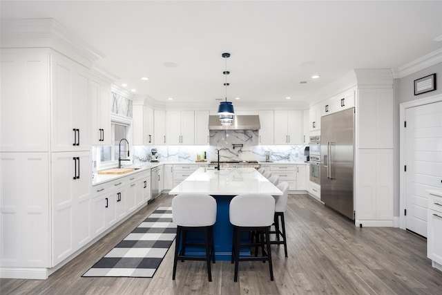 18 Heron Ct, Levittown, NY 11756 - kitchen with stainless steel appliances, wall chimney range hood, dark wood finished floors, backsplash, and a kitchen island with sink